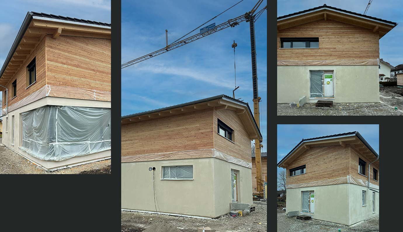 Ein modernes Holzhaus in Aibling wird auf einer Baustelle mit einem Kran im Hintergrund errichtet.