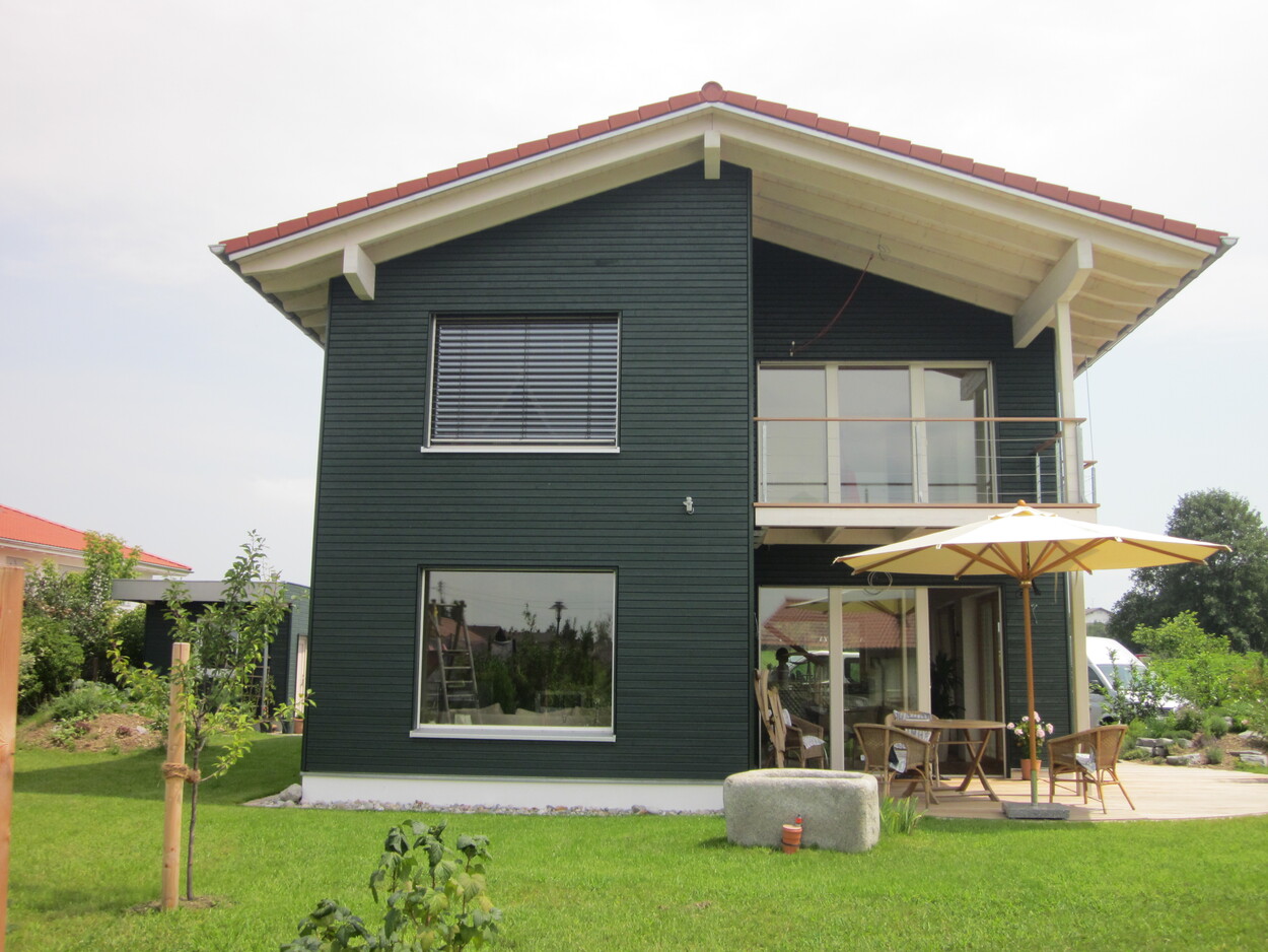 Ein modernes Passivhaus in Breitbrunn mit Terrasse und Sonnenschirm steht in einem gepflegten Garten.