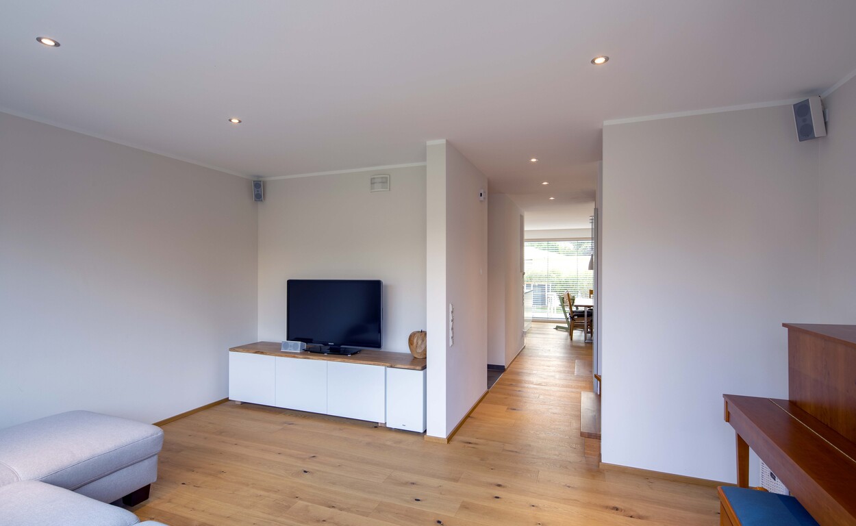 Modernes Wohnzimmer in München mit Holzboden, weißem TV-Schrank und Zugang zum Essbereich im Doppelhaus.