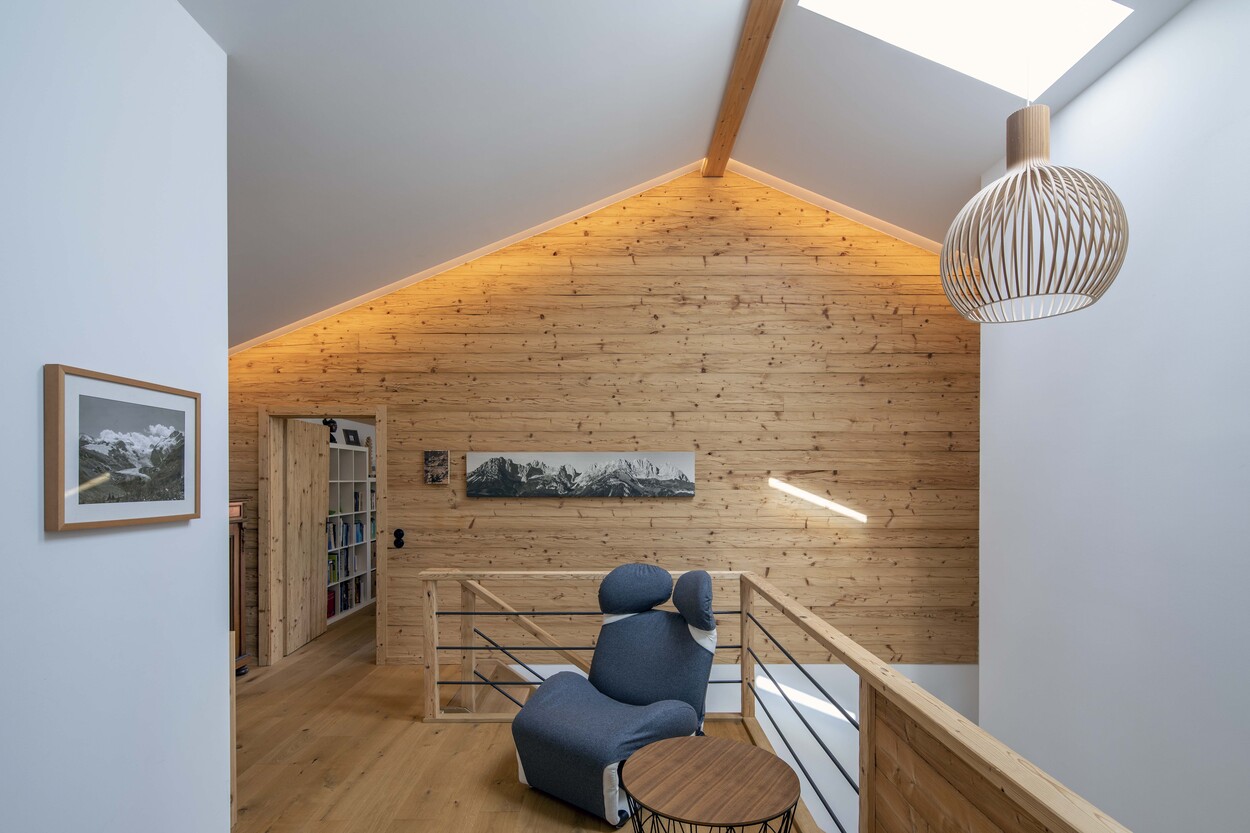 Ein modernes Holzhaus in Schleching mit gemütlichem Interieur und einem blauen Sessel vor einer Holzvertäfelung.