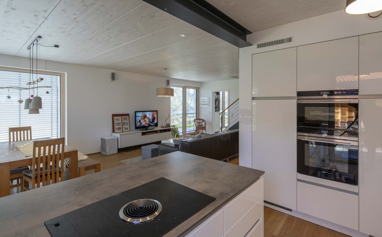 Ein modernes Niedrigenergiehaus in Tuntenhausen präsentiert eine offene Küche und ein stilvolles Wohnzimmer mit TV.