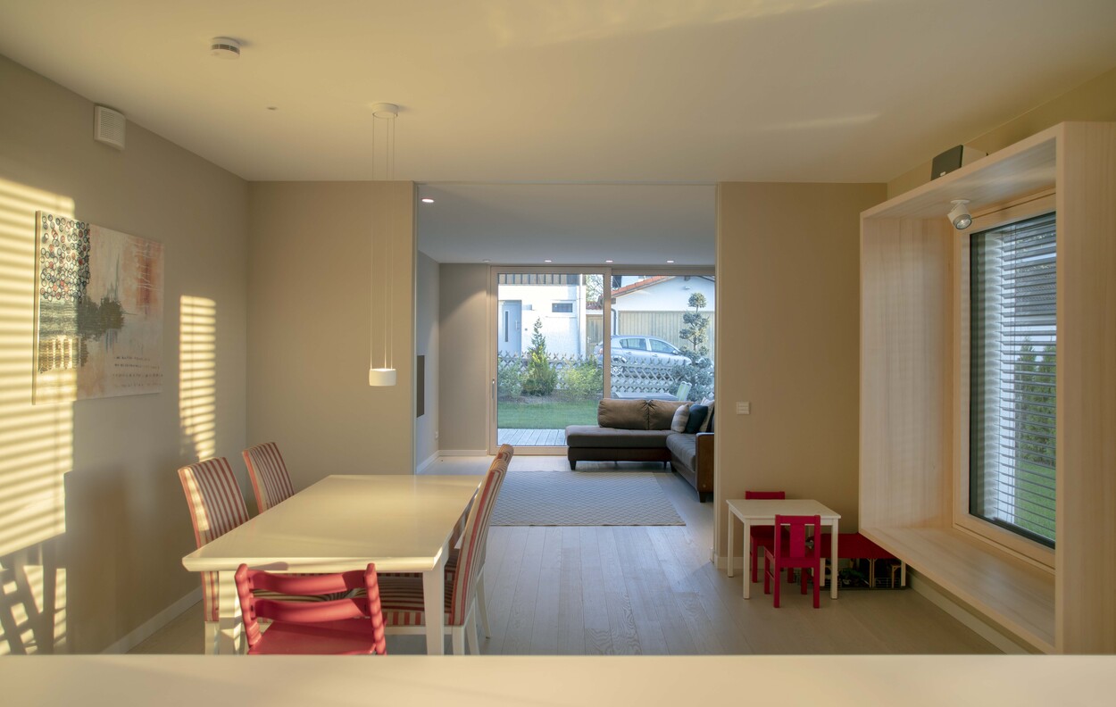 Ein modernes Esszimmer im Passivhaus zeigt einen großen Tisch mit Blick durch ein großes Fenster auf den Garten.