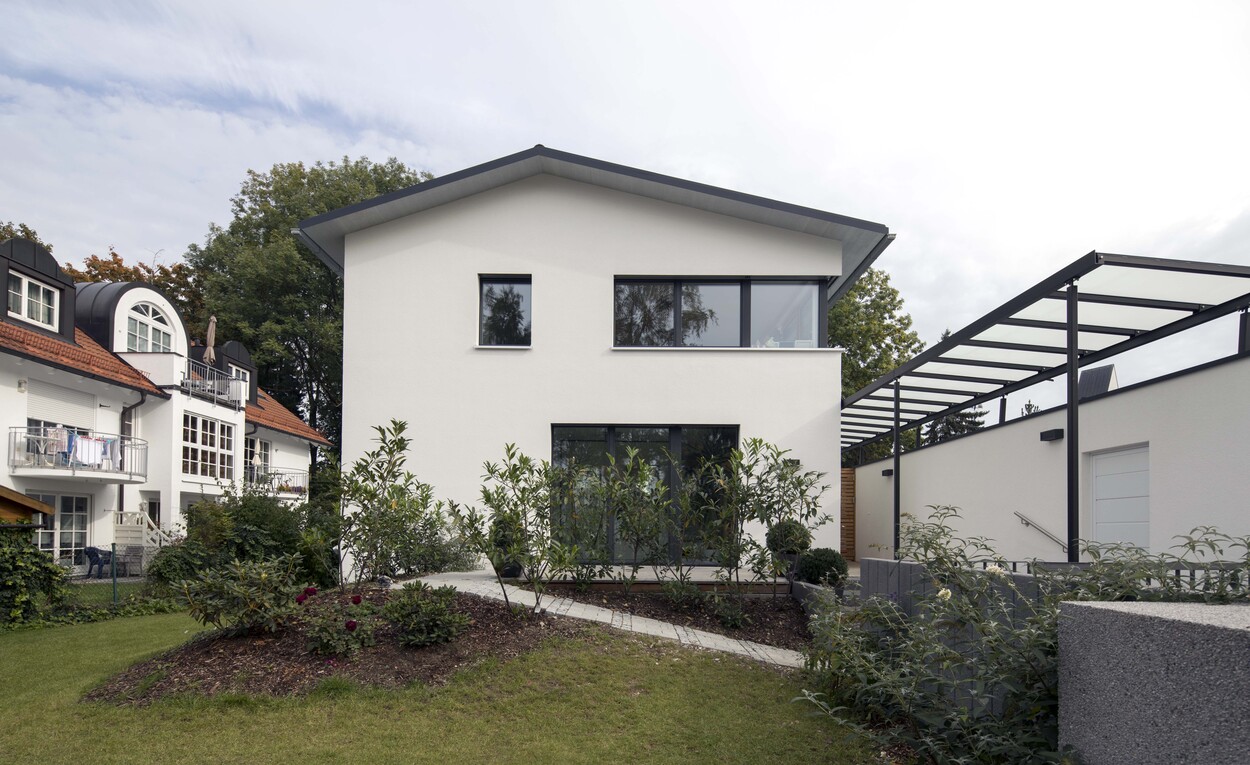 Das Passivhaus in München beeindruckt mit seiner modernen Fassade, großen Fenstern und einem gepflegten Garten.