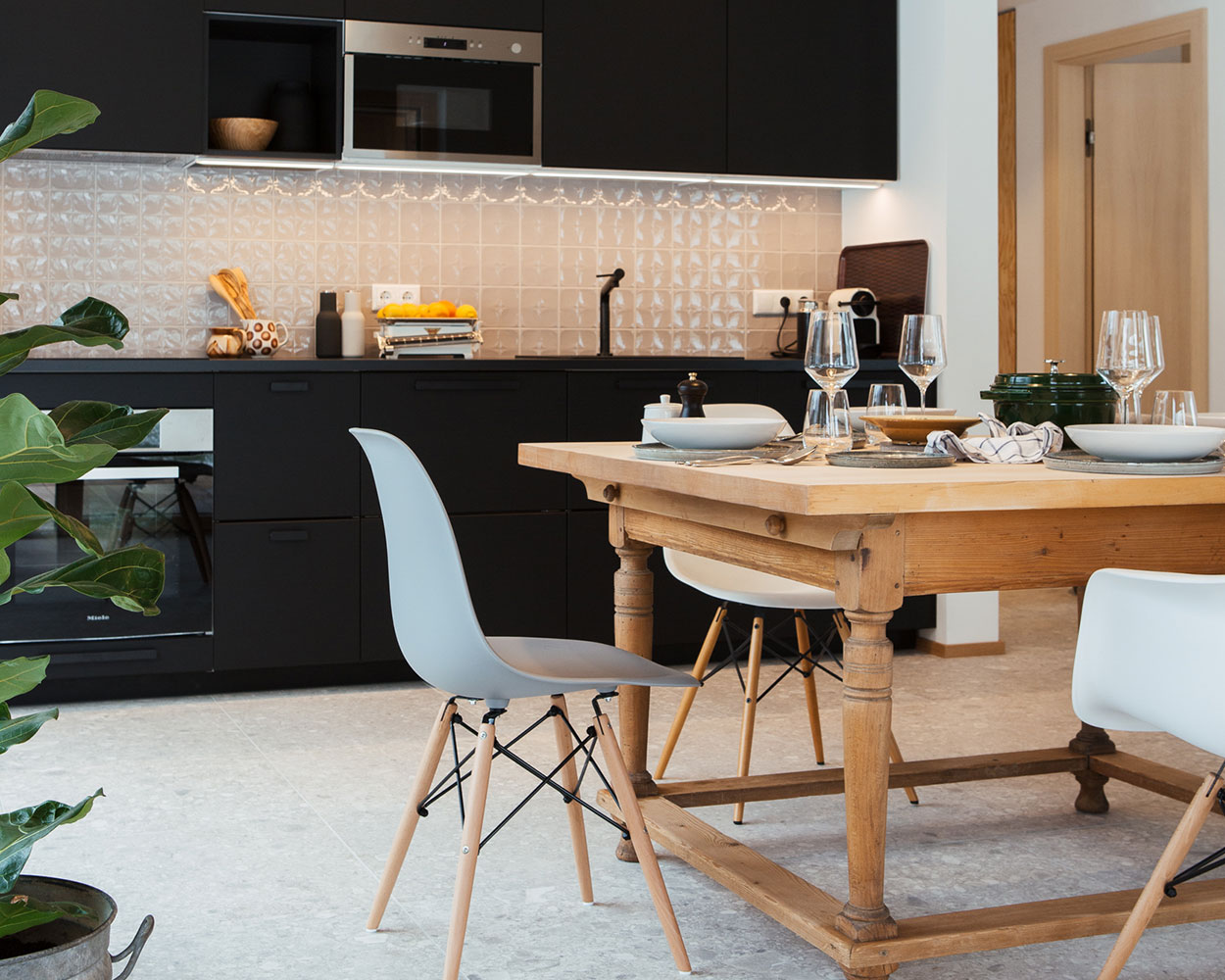 Ein modernes Esszimmer im Chiemgau-Ferienhaus mit stilvollen schwarzen Küchenmöbeln und einem gemütlichen Holztisch.