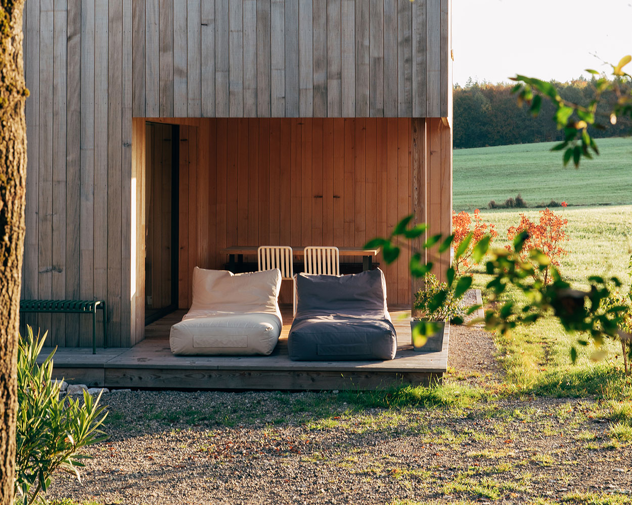 Zwei Sitzsäcke stehen auf der Terrasse eines Holzferienhauses im Chiemgau, umgeben von grüner Landschaft.