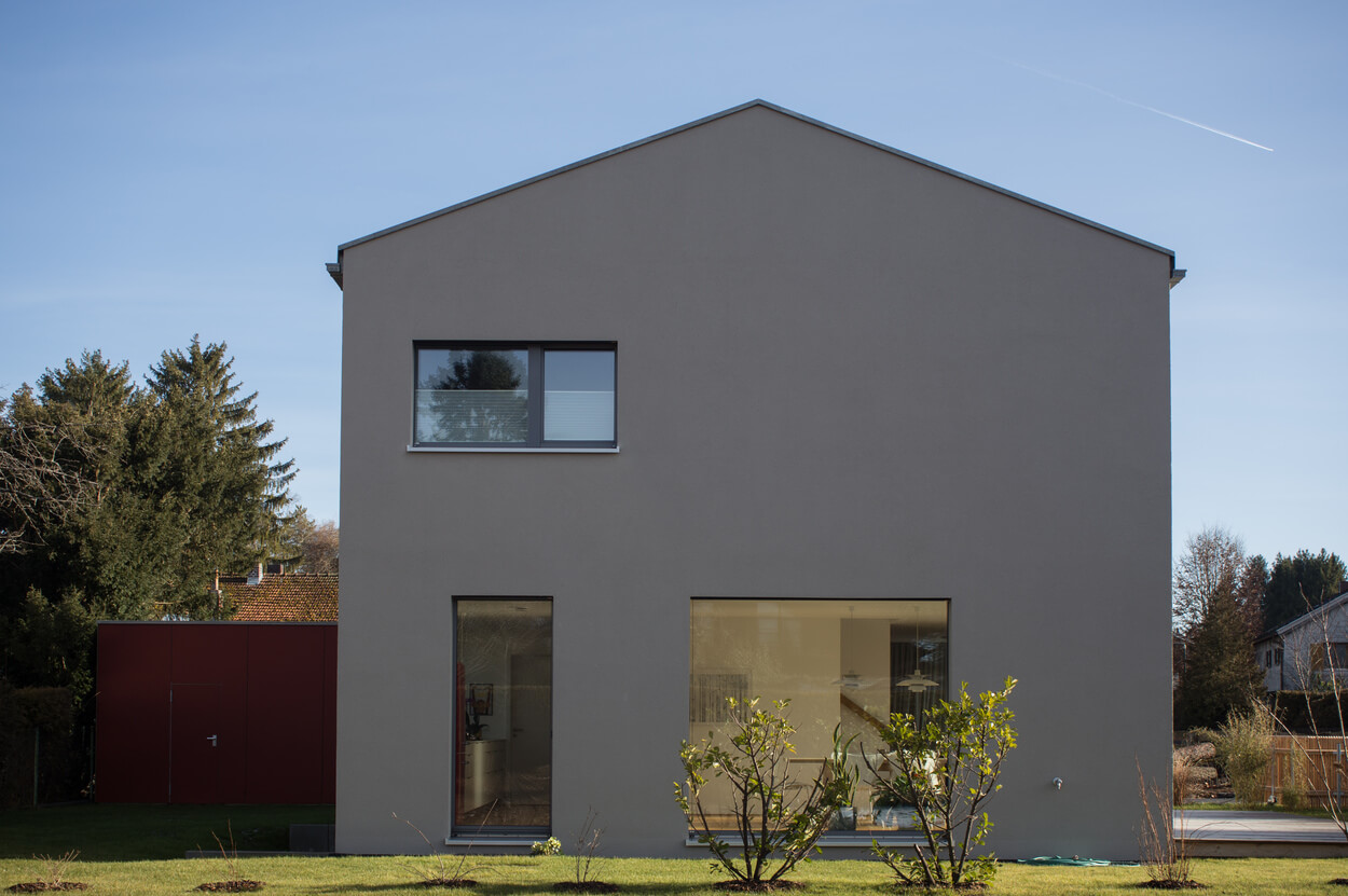 Ein modernes Passivhaus in Baierbrunn präsentiert seine schlichte, energieeffiziente Fassade unter klarem Himmel.