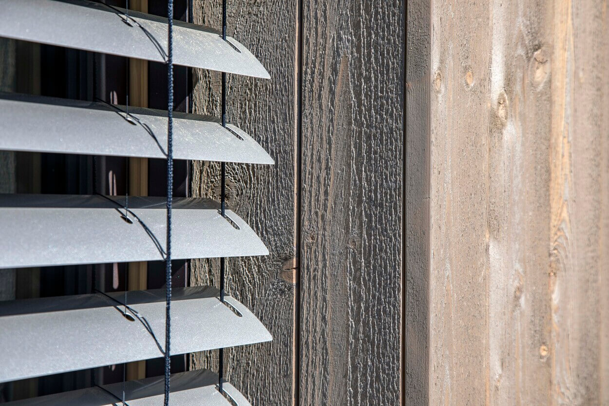 Außenjalousien bieten effektiven Sonnenschutz an der hölzernen Fassade eines Hauses in Otterfing.