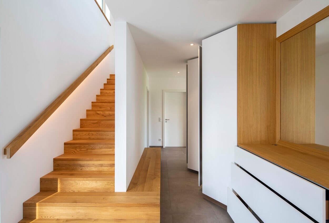 Ein modernes Treppenhaus aus Holz mit klaren Linien schmückt das minimalistische Passivhaus in Pliening.