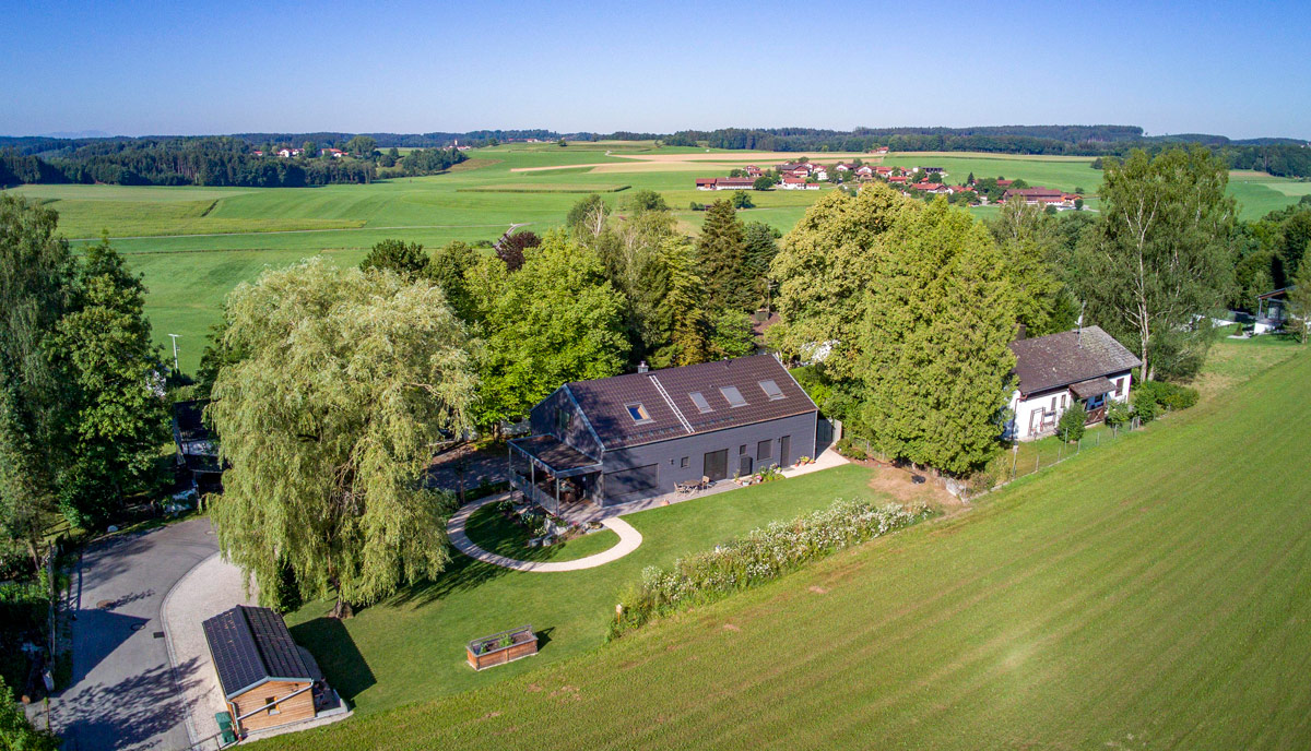 Ein modernes Holzhaus in Glonn liegt malerisch eingebettet zwischen üppigem Grün und weitläufigen Feldern.