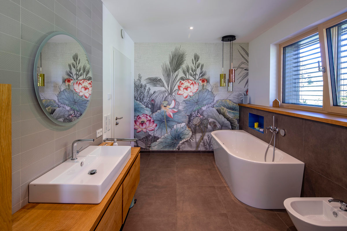 Modernes Badezimmer mit freistehender Badewanne, floralem Wandbild und stilvollen Holzdetails im Holzhaus in Glonn.