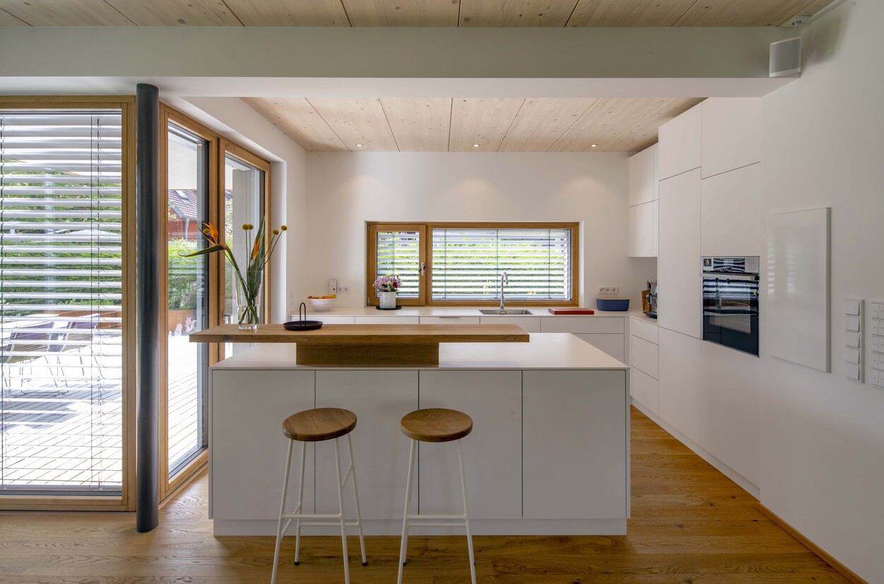 Moderne Küche aus Holz in Gröbenzell, mit viel Tageslicht, weißen Schränken und einem eleganten, minimalistischen Design.