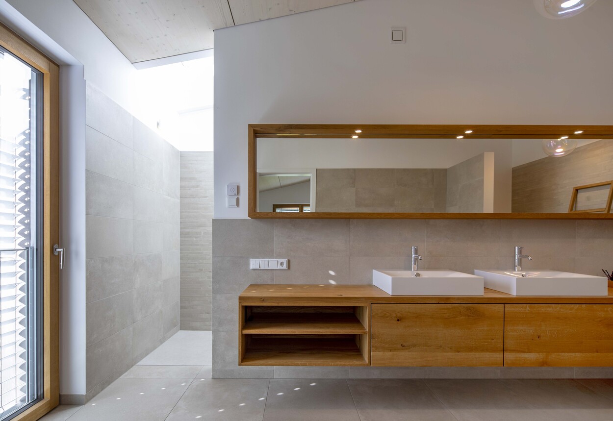 Ein modernes Badezimmer in Gröbenzell zeigt einen eleganten Holzwaschtisch mit zwei stilvollen Waschbecken.