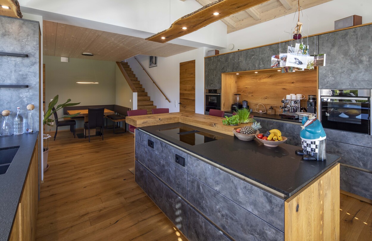 Moderne Küche mit grauen Schränken und Holzelementen, ergänzt durch eine gemütliche Sitzecke im Einfamilienhaus.