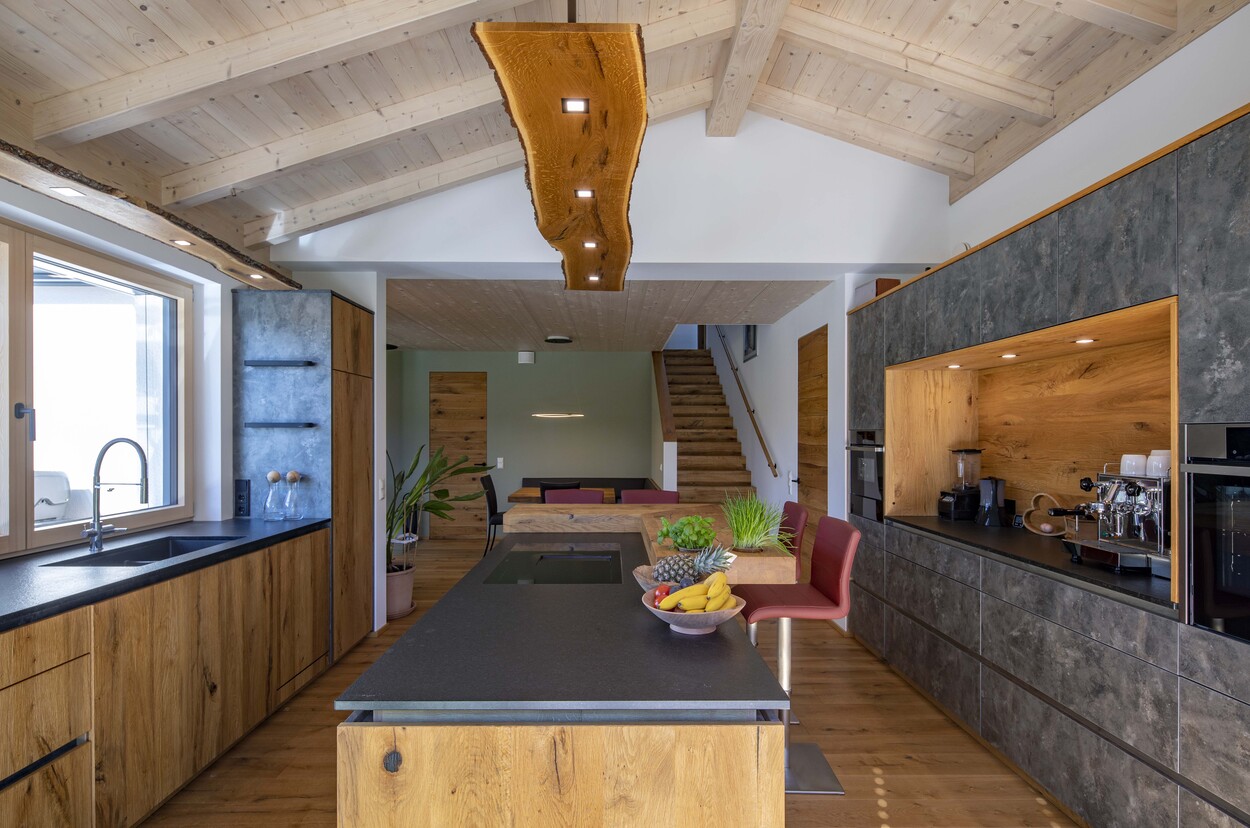 Eine moderne Küche in einem Einfamilienhaus in Prien zeigt Holzelemente und eine großzügige Kochinsel voller frischem Obst.