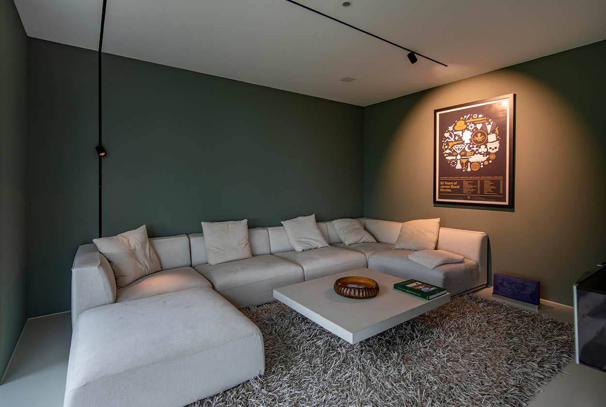 Ein modernes Wohnzimmer mit grauem Sofa, flauschigem Teppich und dekorativem Poster an der stilvoll grünen Wand.