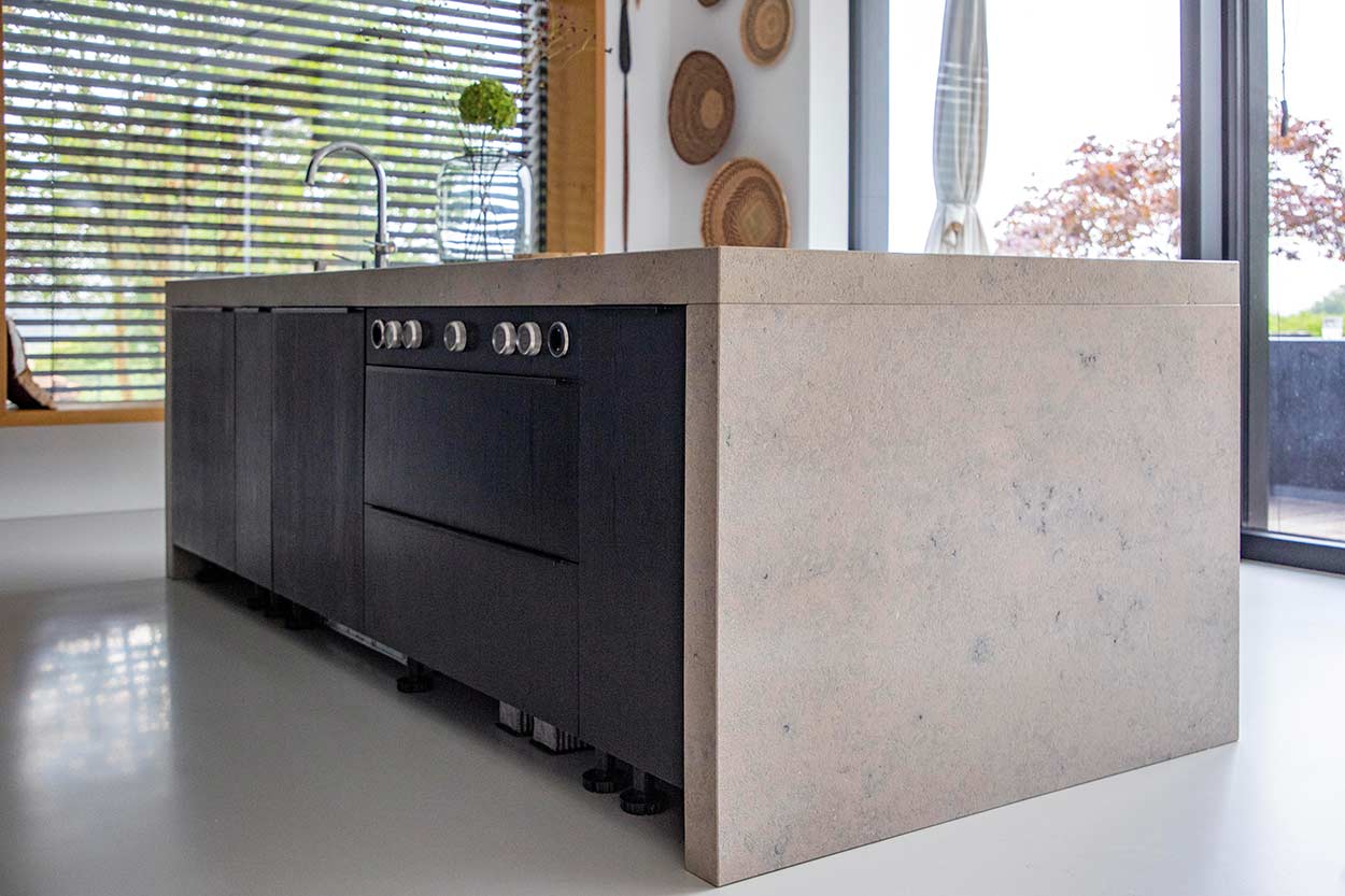 Eine moderne Küche mit heller Kücheninsel, großem Herd, umgeben von Fenstern und dekorativen Körben an der Wand.