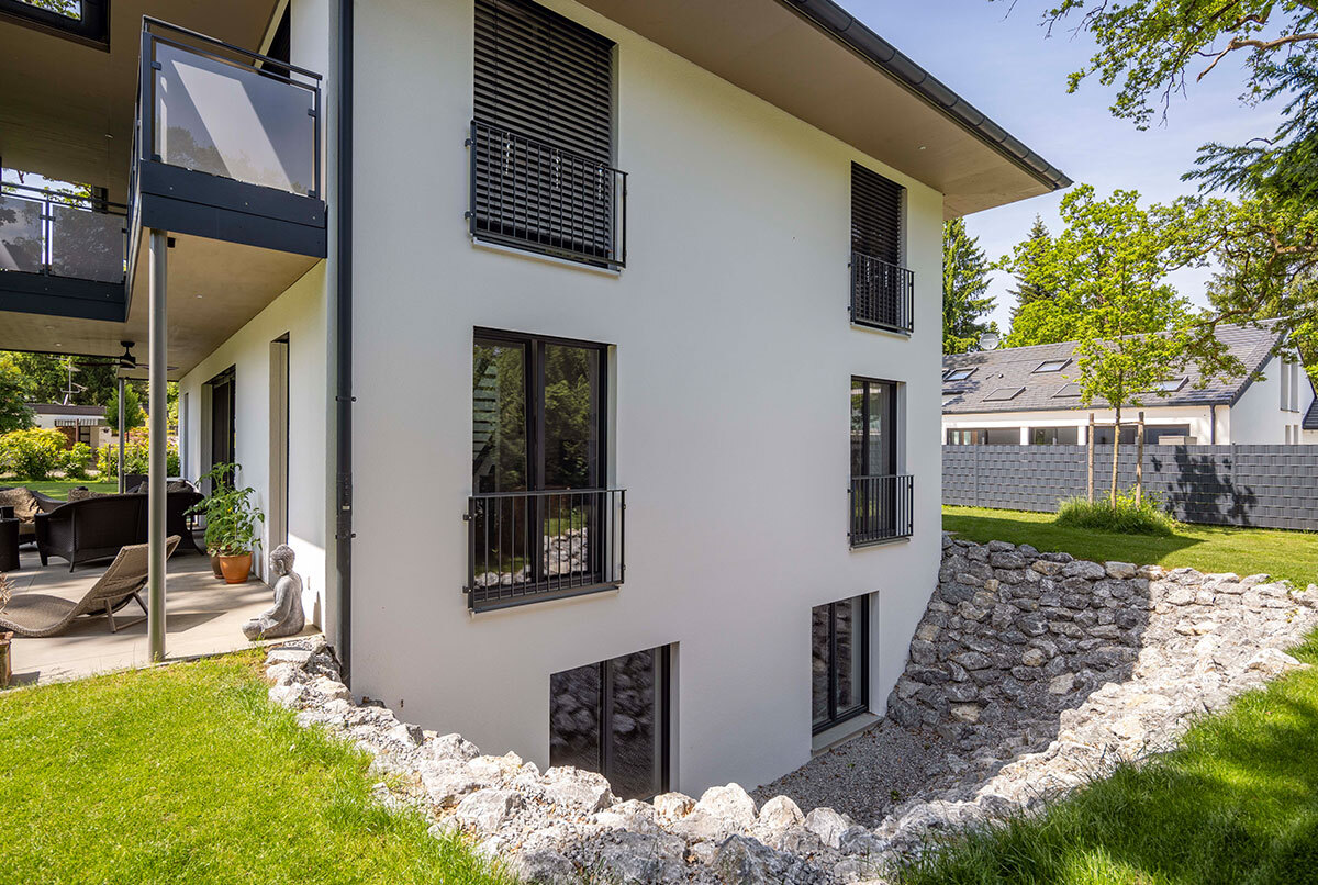 Ein modernes Energiesparhaus im Münchner Kreis mit großen Fenstern, einer Terrasse und einem gepflegten Garten.