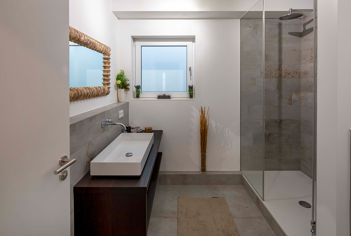 Modernes Gästebad mit stilvollem Waschbecken und großer Dusche in einem energiesparenden Haus im Kreis München.