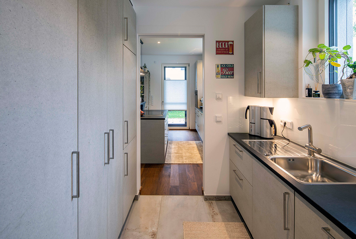 Moderne Küche mit eleganten Schränken und großem Fenster in einem energiesparenden Haus im Kreis München.