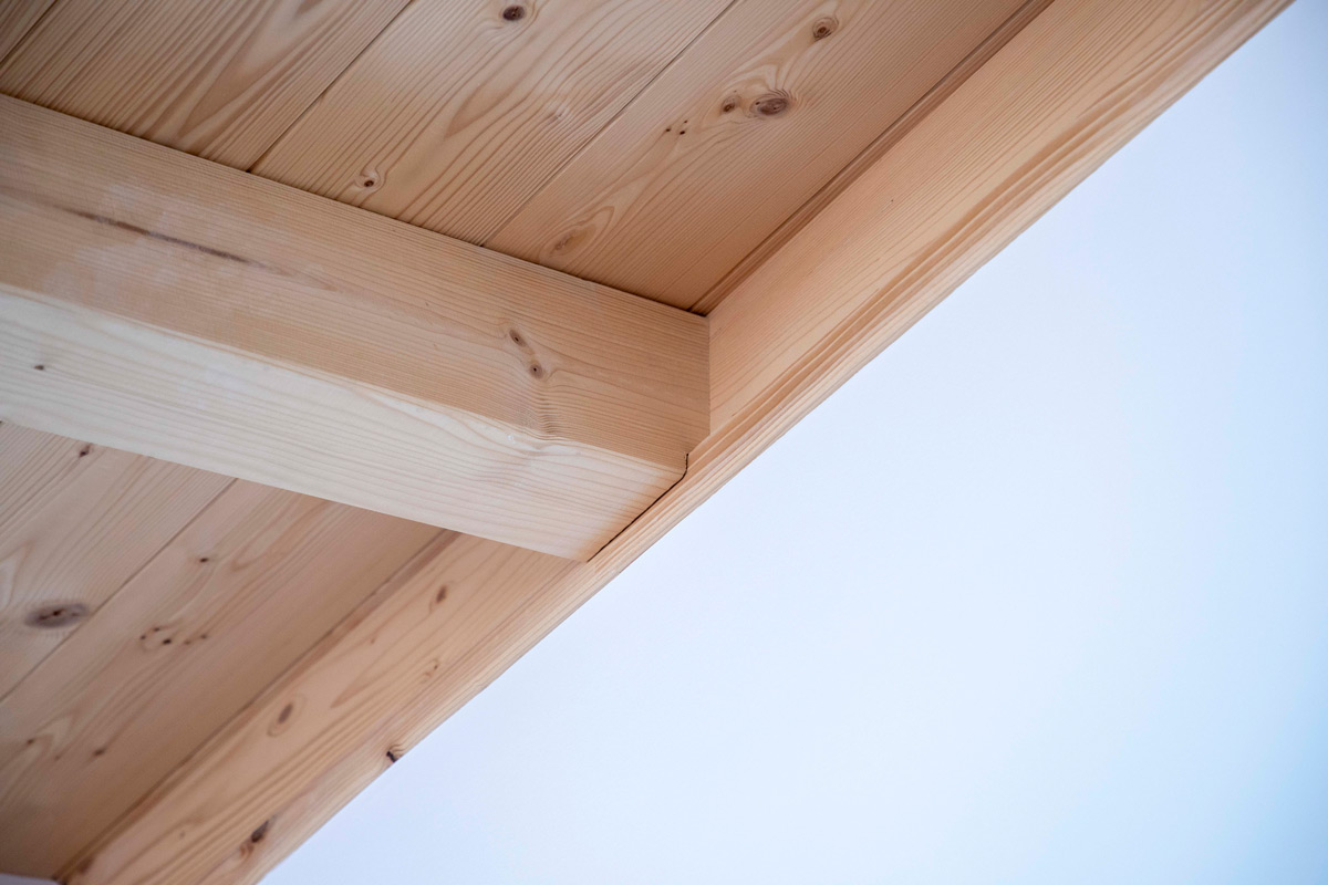 Eine Holzdecke in einem modernen Haus in Neubeuern zeigt sichtbare Balken und natürliche Holzmaserung.