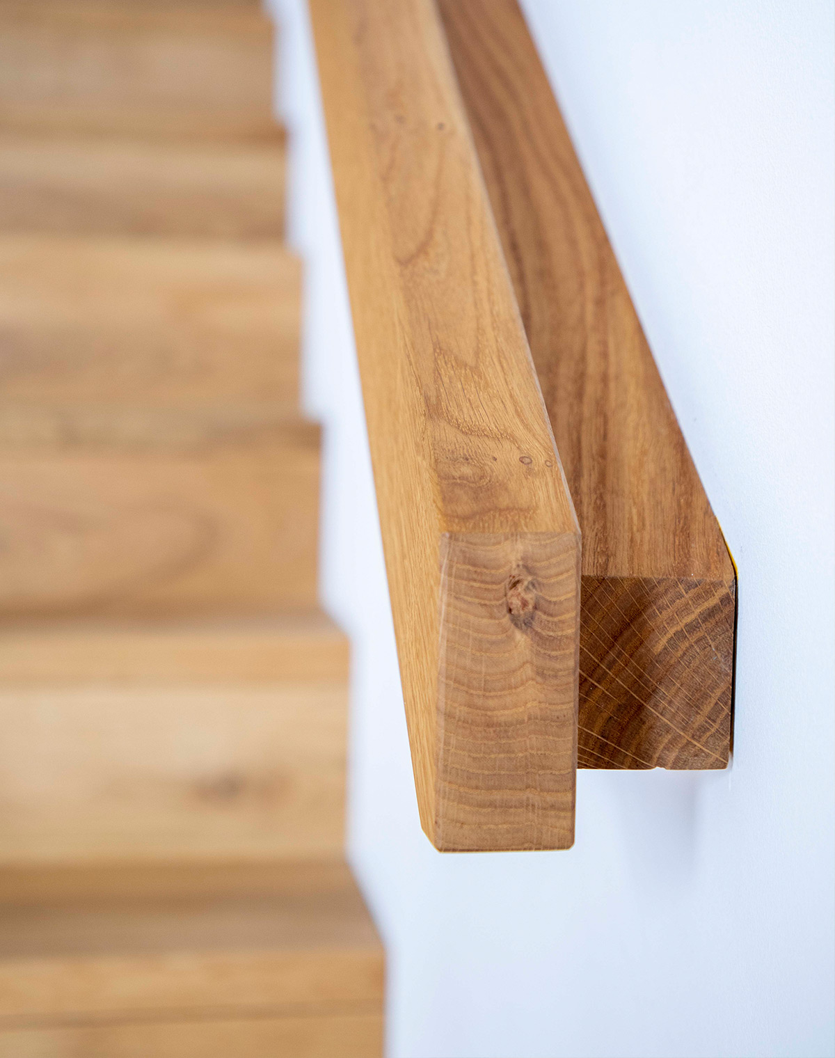 Detailaufnahme einer Holztreppe in einem Holzhaus in Neubeuern, die das elegante Design des Handlaufs zeigt.