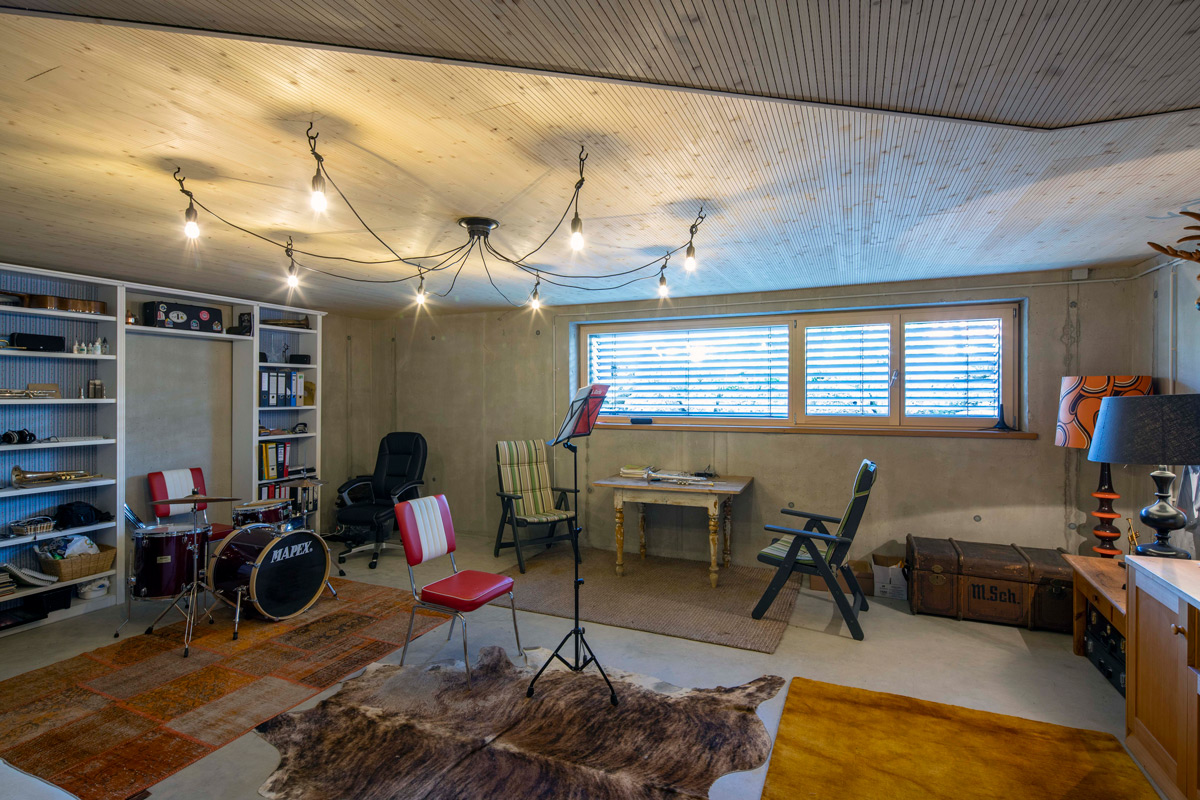 Ein Musikzimmer in einem Holzhaus in Neubeuern zeigt ein Schlagzeug, Teppiche und stimmungsvolle Beleuchtung.