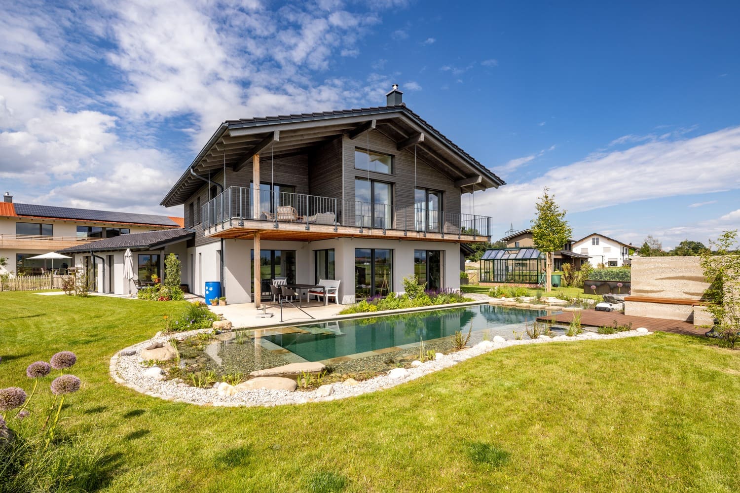 Holzbau in Chieming mit Badeteich von der Südseite, Garten und Sitzecke