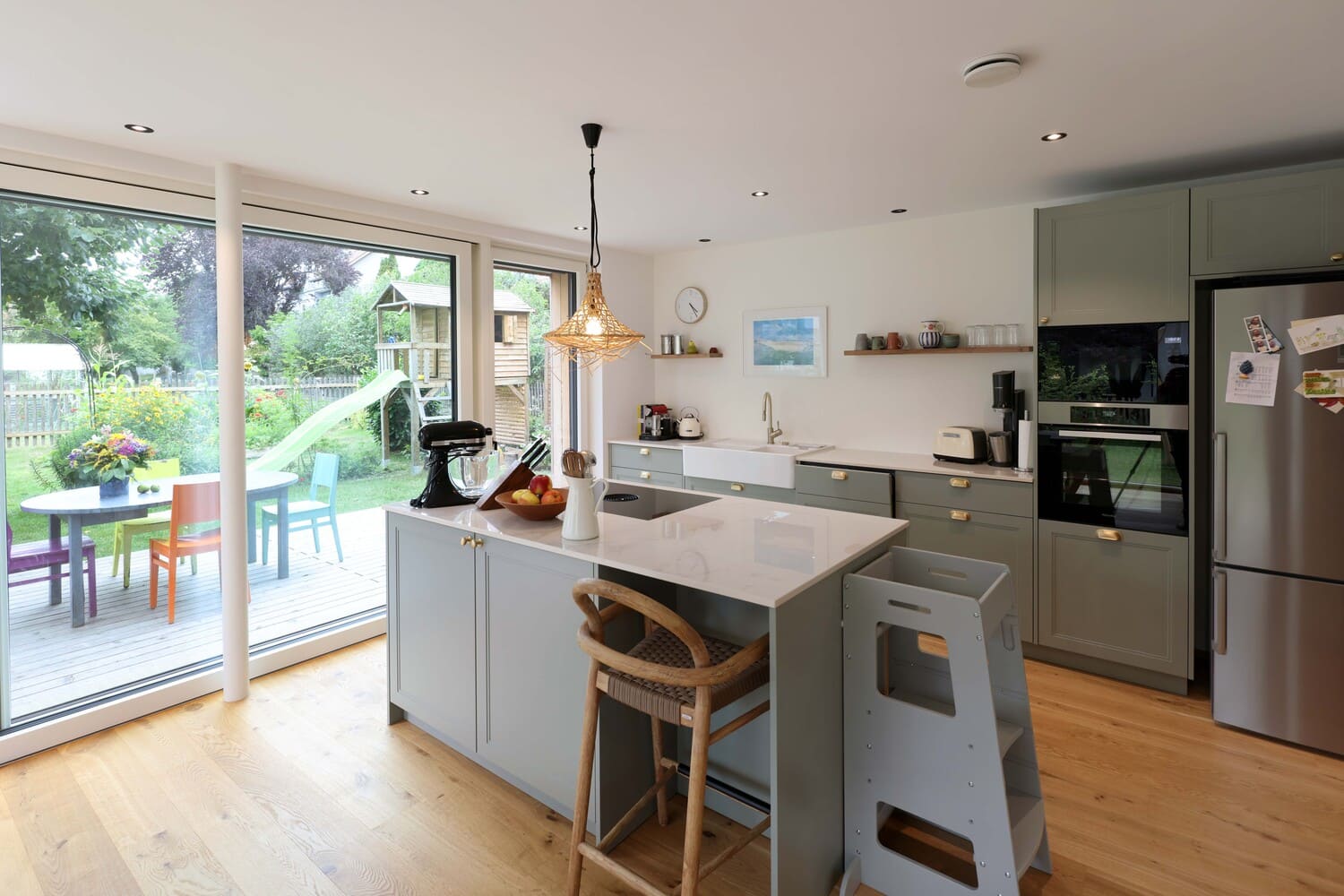 graugrüne Küche im Holzhaus in Zolling mit Kinderstühlen