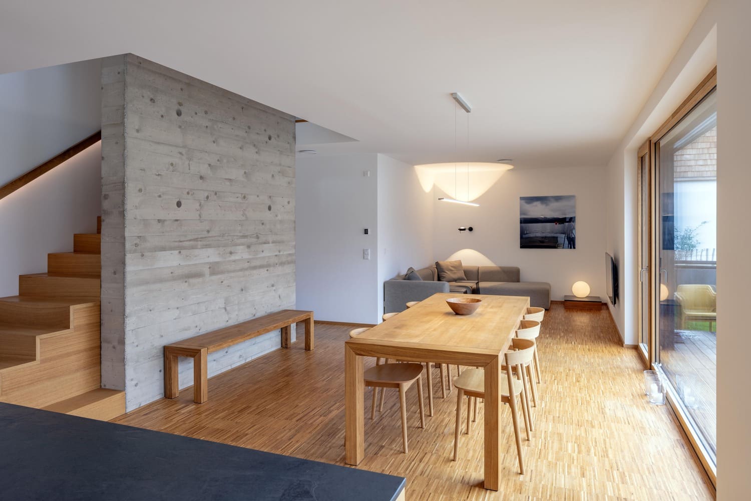 Wohnbereich mit Holztreppe an Sichtbeton