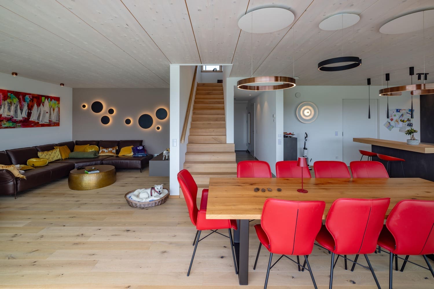 verputztes Holzhaus in Weilheim, Einblick in Wohn-Esszimmerbereich mit Treppenaufgang, weiße Sicht-Holzdecke