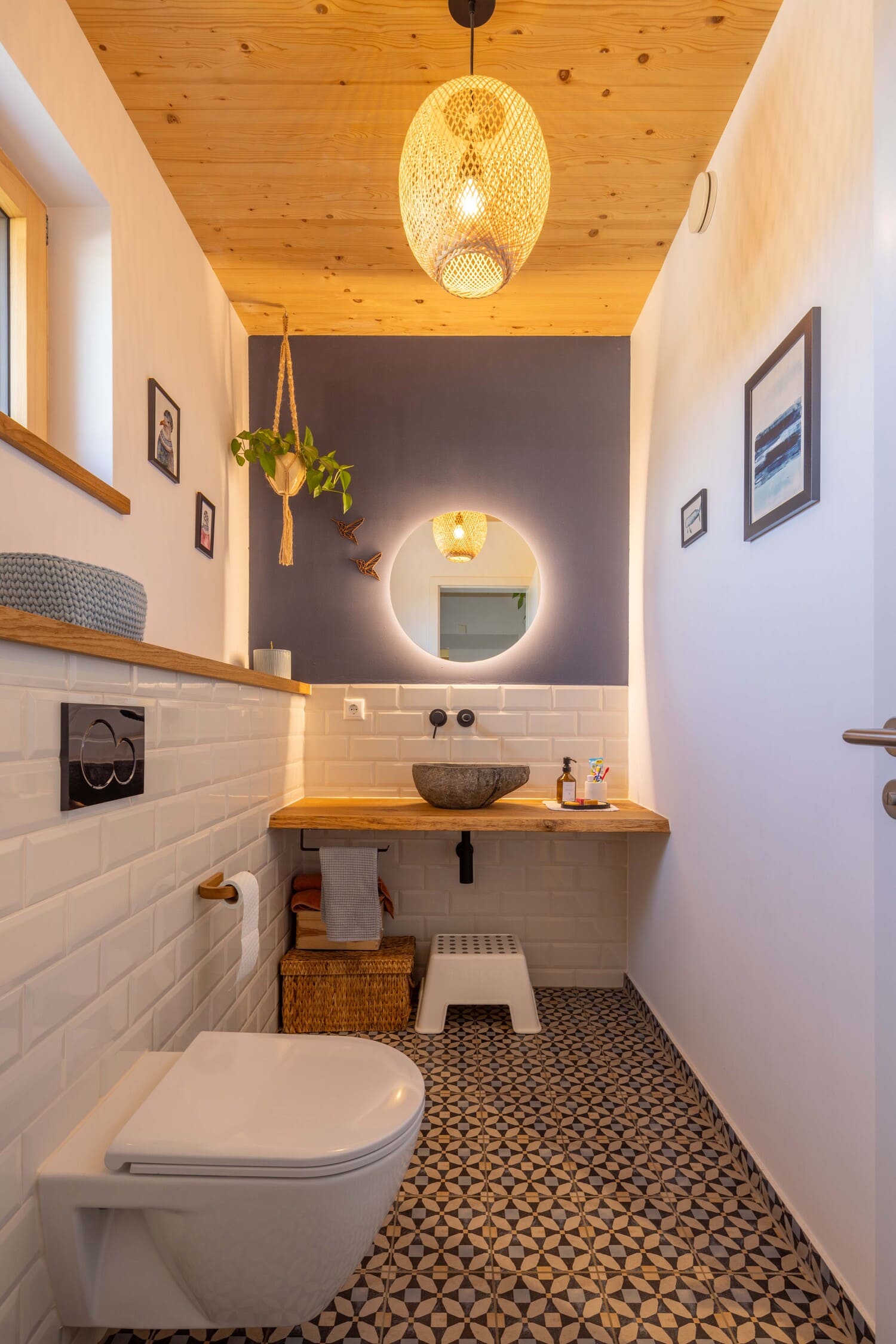 Ein modernes Badezimmer mit Holzelementen und geometrischen Fliesen wirkt durch stilvolle Beleuchtung einladend und harmonisch.